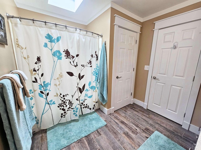 bathroom featuring a shower with curtain, a skylight, baseboards, and wood finished floors