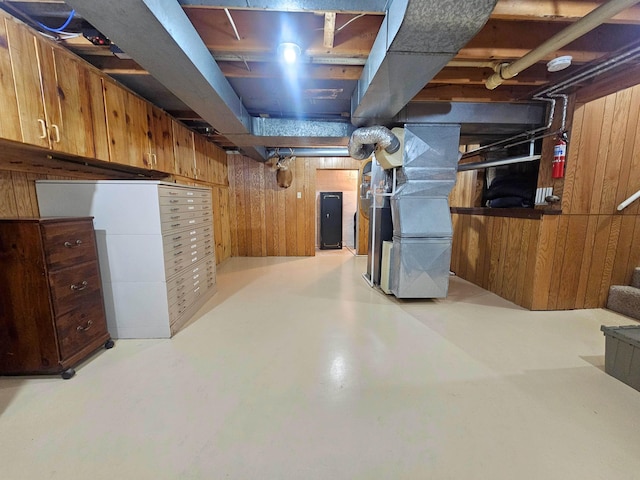 unfinished basement featuring heating unit and wooden walls