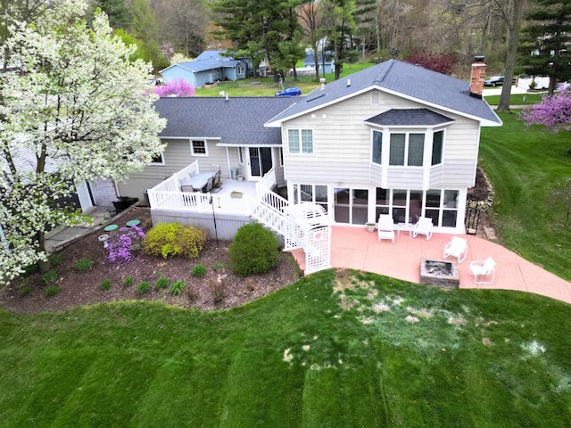 rear view of house with a lawn, a patio area, a sunroom, and a shingled roof