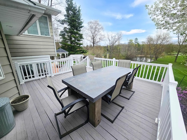 wooden terrace featuring a yard, outdoor dining area, and a water view