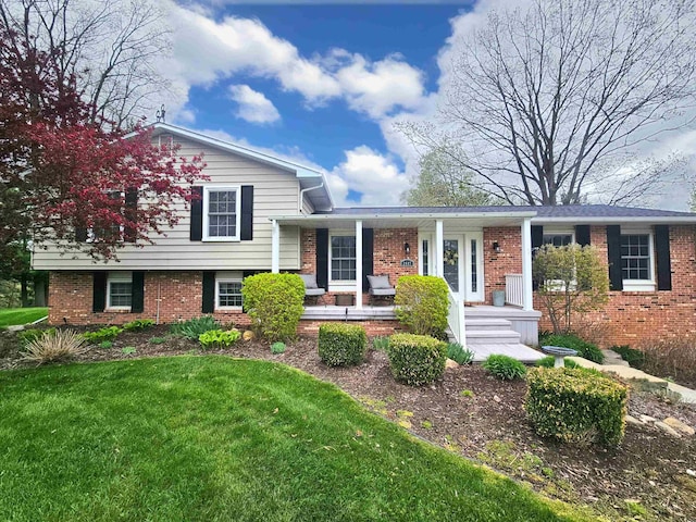 tri-level home with a porch, a front lawn, and brick siding