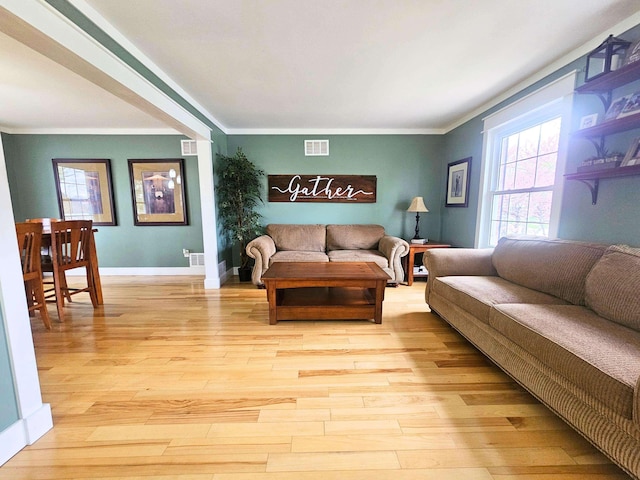 living room with crown molding, visible vents, and light wood-type flooring