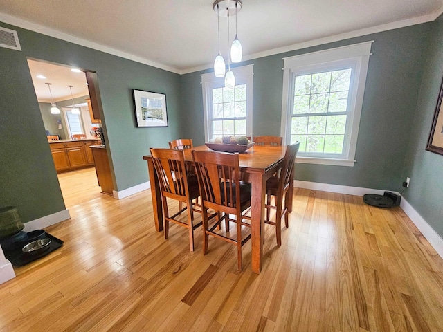 dining room with crown molding, baseboards, light wood-type flooring, and visible vents