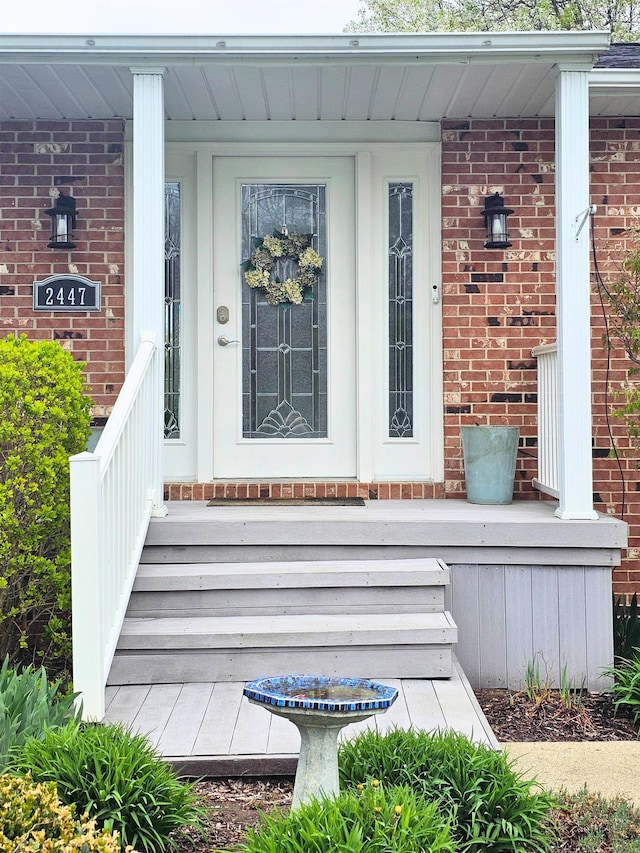 property entrance with covered porch and brick siding