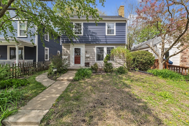 view of front of property featuring fence, a chimney, and a front lawn