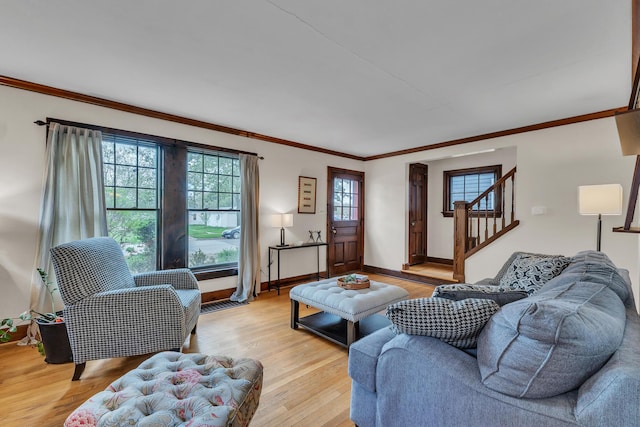 living area with light wood-type flooring, ornamental molding, baseboards, and stairway
