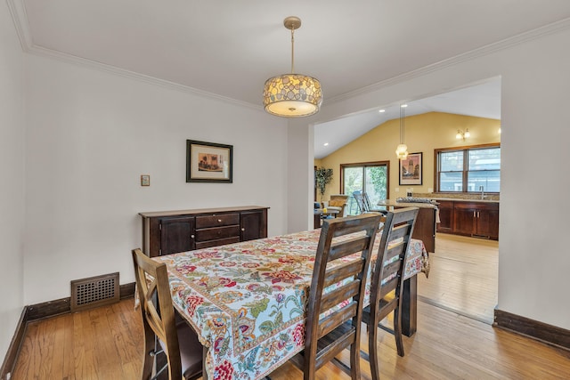 dining room featuring baseboards, ornamental molding, light wood-style flooring, and visible vents