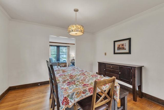 dining room featuring crown molding, baseboards, and light wood finished floors