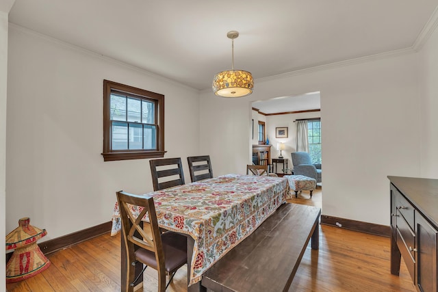 dining room featuring baseboards, wood-type flooring, and crown molding