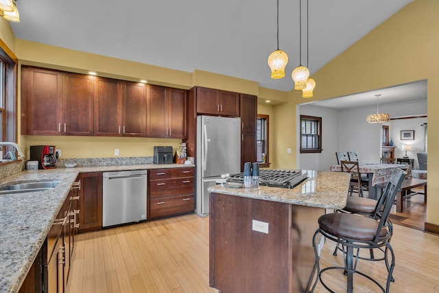 kitchen featuring a sink, light wood finished floors, stainless steel appliances, and a kitchen bar