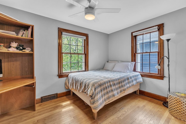 bedroom featuring a ceiling fan, baseboards, visible vents, and light wood-style flooring
