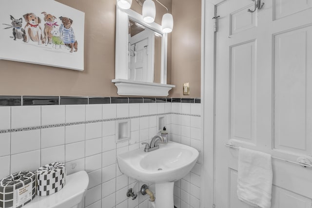 bathroom with a sink, tile walls, and a wainscoted wall