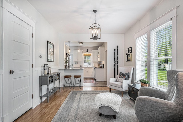 living area featuring a healthy amount of sunlight, wood finished floors, and a chandelier