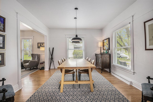 dining space featuring baseboards, wood finished floors, and baseboard heating