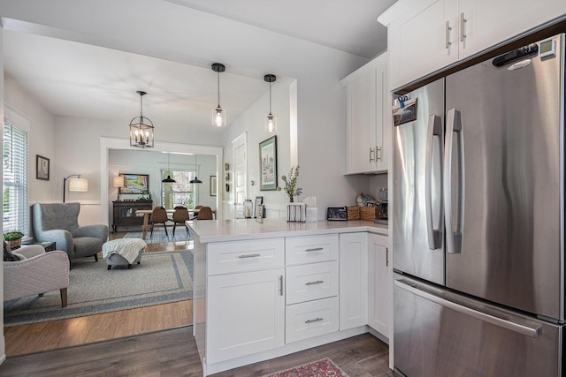 kitchen with dark wood-style flooring, light countertops, freestanding refrigerator, a peninsula, and white cabinetry
