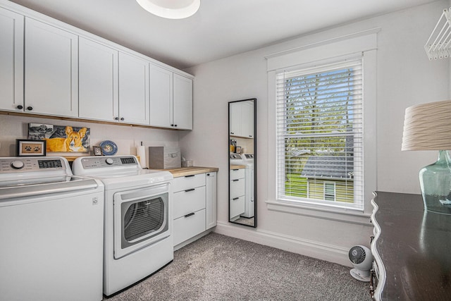 washroom featuring baseboards, cabinet space, light carpet, and washing machine and clothes dryer