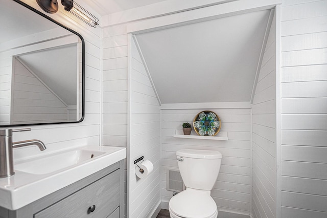 half bath featuring toilet, lofted ceiling, and vanity
