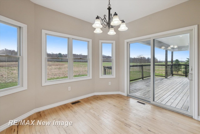 unfurnished room with baseboards, a chandelier, visible vents, and light wood-type flooring