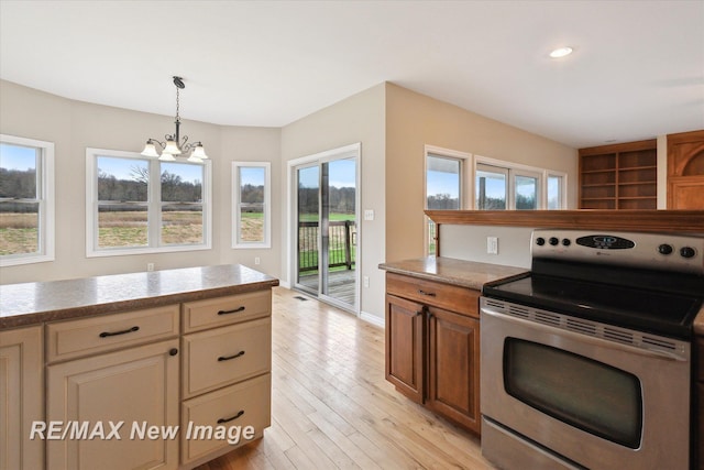 kitchen featuring pendant lighting, stainless steel range with electric cooktop, light countertops, a notable chandelier, and light wood-style flooring