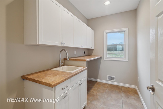 laundry room featuring visible vents, baseboards, recessed lighting, a sink, and light tile patterned floors