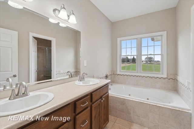 full bathroom featuring a whirlpool tub, tile patterned floors, a sink, and a stall shower