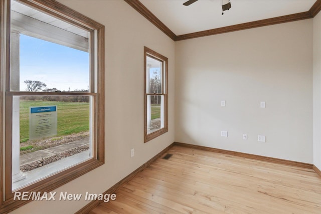 unfurnished room featuring light wood finished floors, a ceiling fan, baseboards, visible vents, and ornamental molding