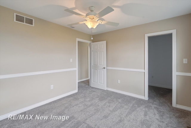 unfurnished bedroom with a walk in closet, baseboards, carpet, and visible vents