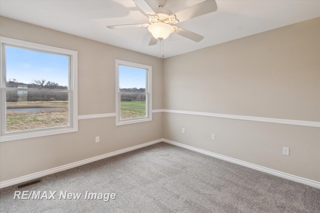 carpeted empty room featuring visible vents, baseboards, and ceiling fan