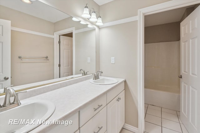 bathroom featuring baseboards, double vanity, tile patterned floors, and a sink