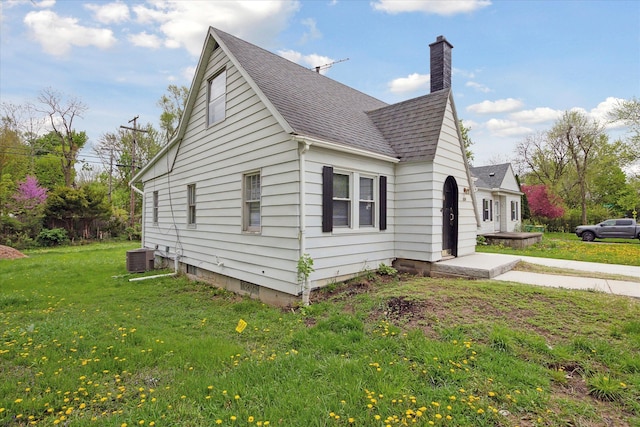 224 N Hewitt Rd, Ypsilanti, MI 48197 - view of side of property featuring a shingled roof, a chimney, a yard, and central AC unit