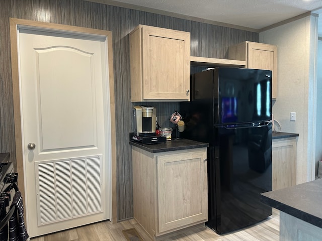 kitchen featuring visible vents, freestanding refrigerator, light brown cabinetry, and dark countertops