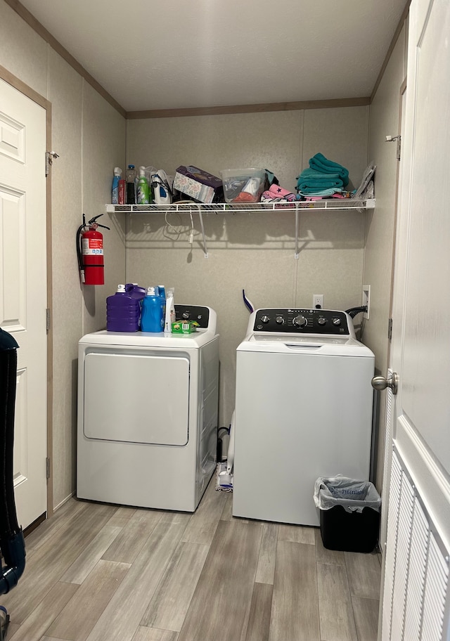 washroom with washing machine and clothes dryer, laundry area, ornamental molding, and light wood-style flooring