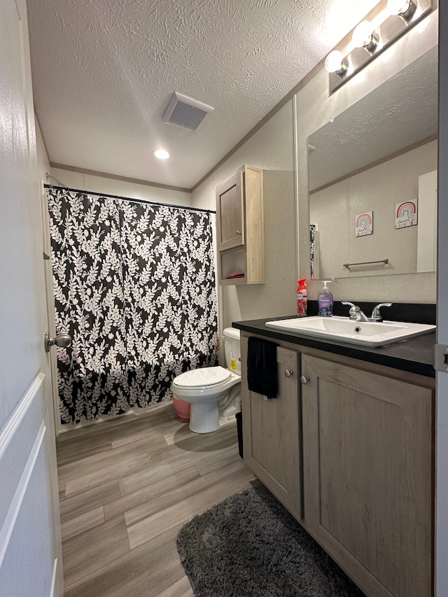 full bath featuring a textured ceiling, visible vents, wood finished floors, vanity, and toilet