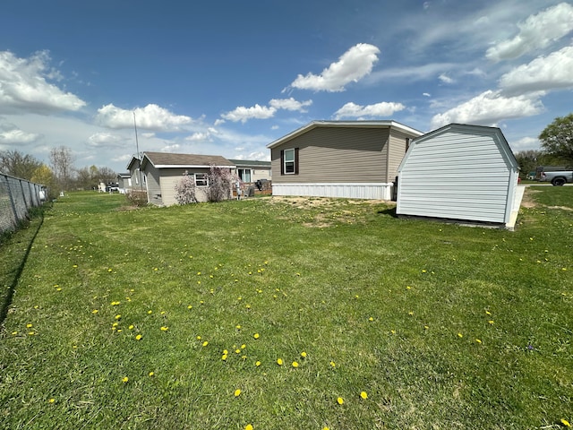 exterior space featuring a yard, fence, an outbuilding, and a storage unit