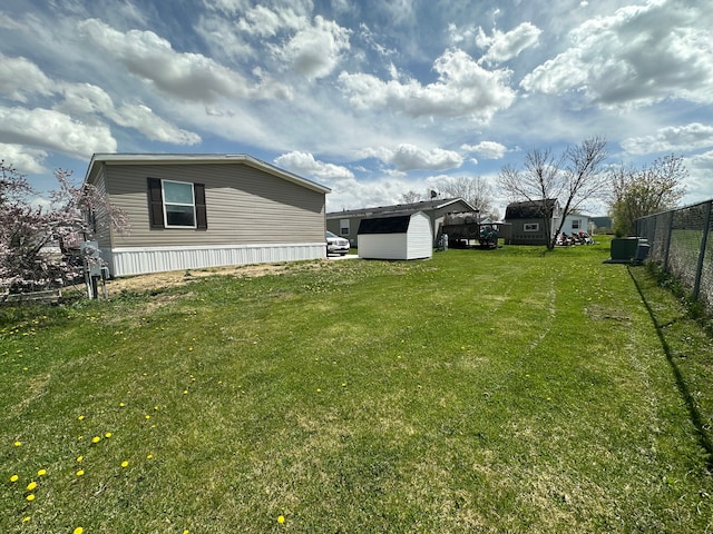 view of yard featuring fence, a storage unit, and an outdoor structure
