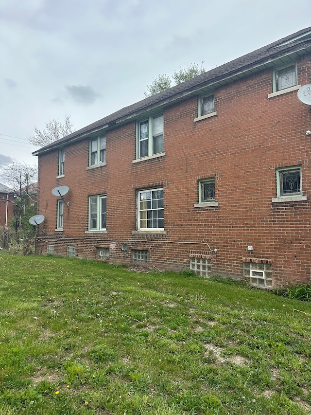 view of side of property featuring a lawn and brick siding