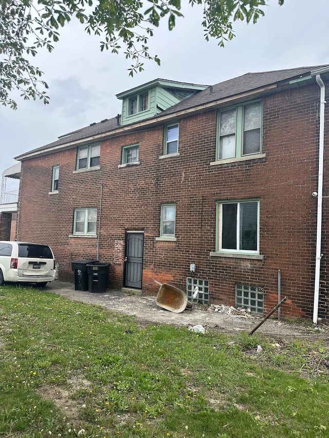 rear view of house with a lawn and brick siding