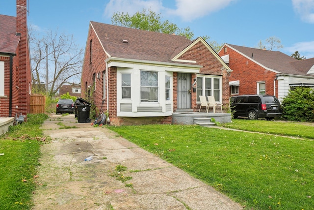 14141 Edmore Dr, Detroit, MI 48205 - bungalow-style house with fence, a shingled roof, a front yard, brick siding, and driveway