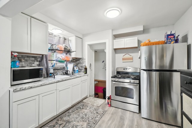 14141 Edmore Dr, Detroit, MI 48205 - kitchen with light wood-style floors, white cabinetry, decorative backsplash, and appliances with stainless steel finishes