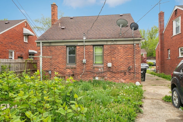14141 Edmore Dr, Detroit, MI 48205 - rear view of house featuring fence, a shingled roof, a chimney, and brick siding