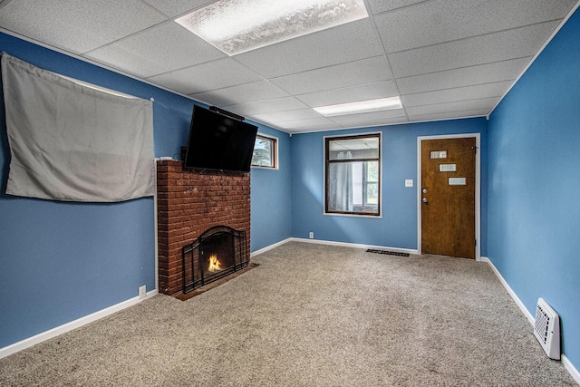 unfurnished living room with a brick fireplace, visible vents, a paneled ceiling, and carpet