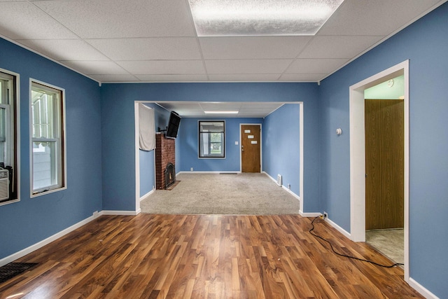 empty room featuring baseboards, a drop ceiling, wood finished floors, and visible vents