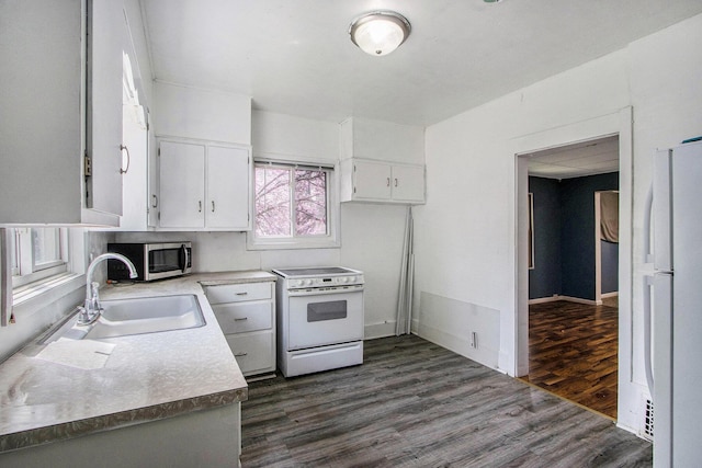 kitchen featuring white appliances, dark wood-style floors, light countertops, white cabinetry, and a sink