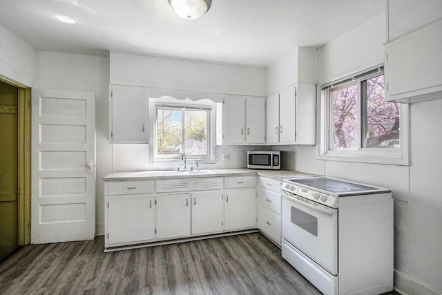 kitchen with white electric stove, a sink, light countertops, white cabinets, and stainless steel microwave