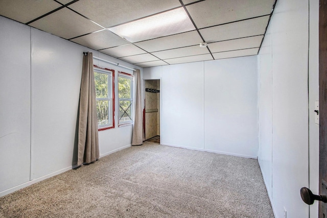 spare room featuring baseboards, carpet flooring, and a drop ceiling