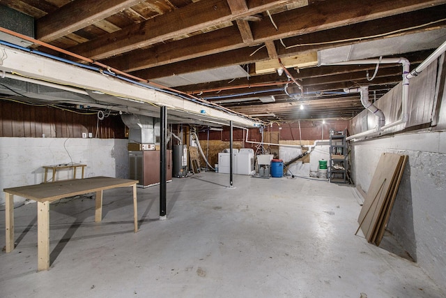 unfinished basement with water heater, heating unit, and washing machine and dryer