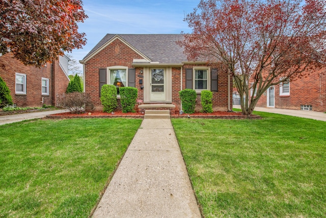 bungalow-style home with brick siding, a front yard, and roof with shingles