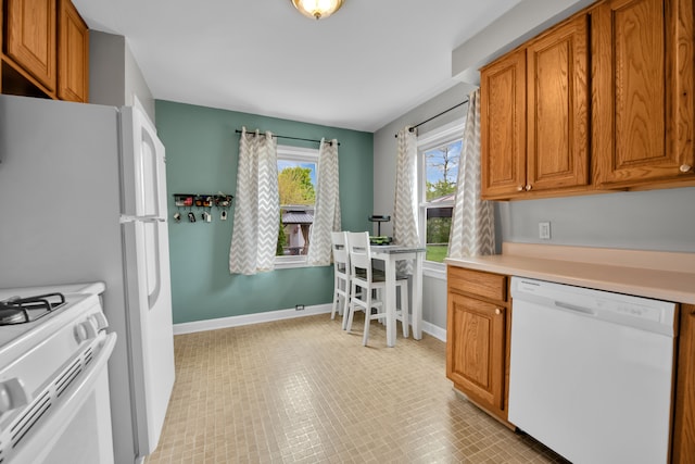 kitchen featuring brown cabinetry, light countertops, baseboards, and white appliances