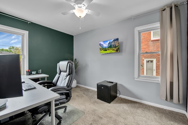 carpeted office space featuring baseboards and ceiling fan