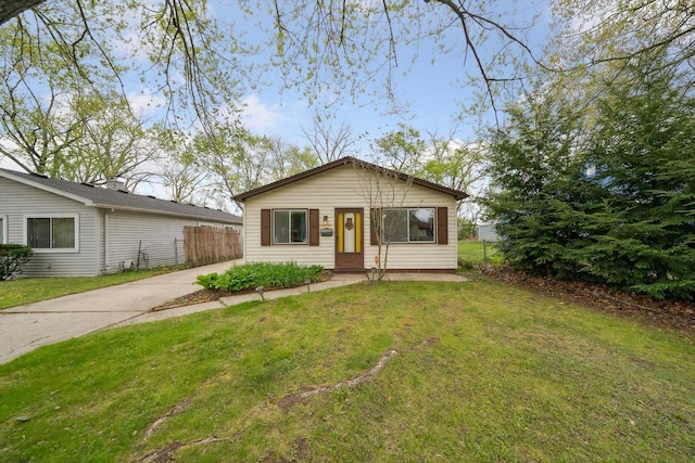 view of front of house featuring fence, concrete driveway, and a front yard